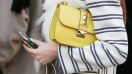 Mujer posa con un bolso amarillo de Valentino antes del desfile de Cristiano Burani en Milan Fashion Week 2016.