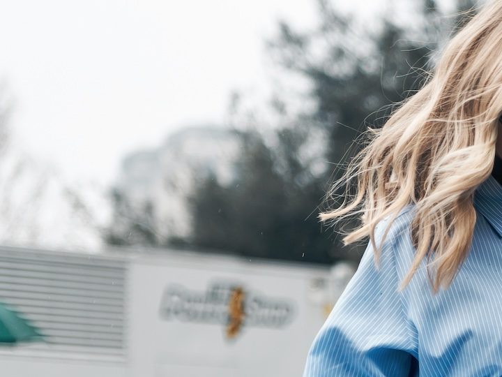 Mujer rubia usando una camisa oversized, una de las prendas básicas del guardarropa que no pasa de moda.