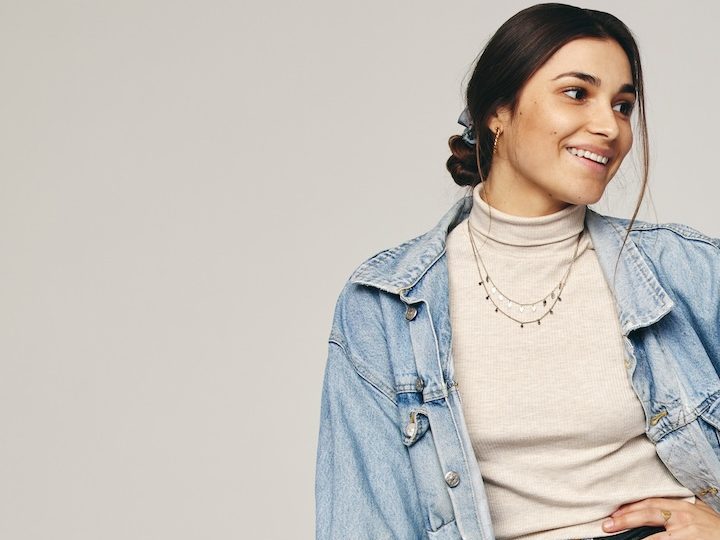 Mujer sentada posa usando una chaqueta de mezclilla oversized.