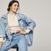 Mujer sentada posa usando una chaqueta de mezclilla oversized.