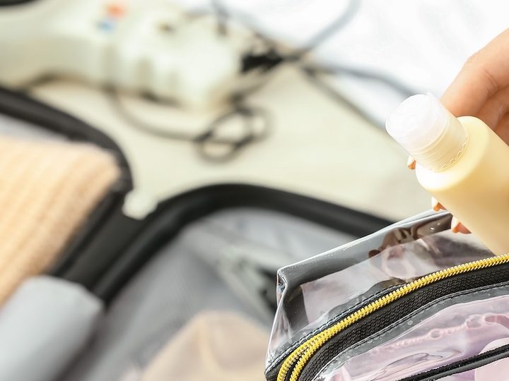 Mujer guarda sus cosméticos en una bolsa de viaje de plástico transparente.