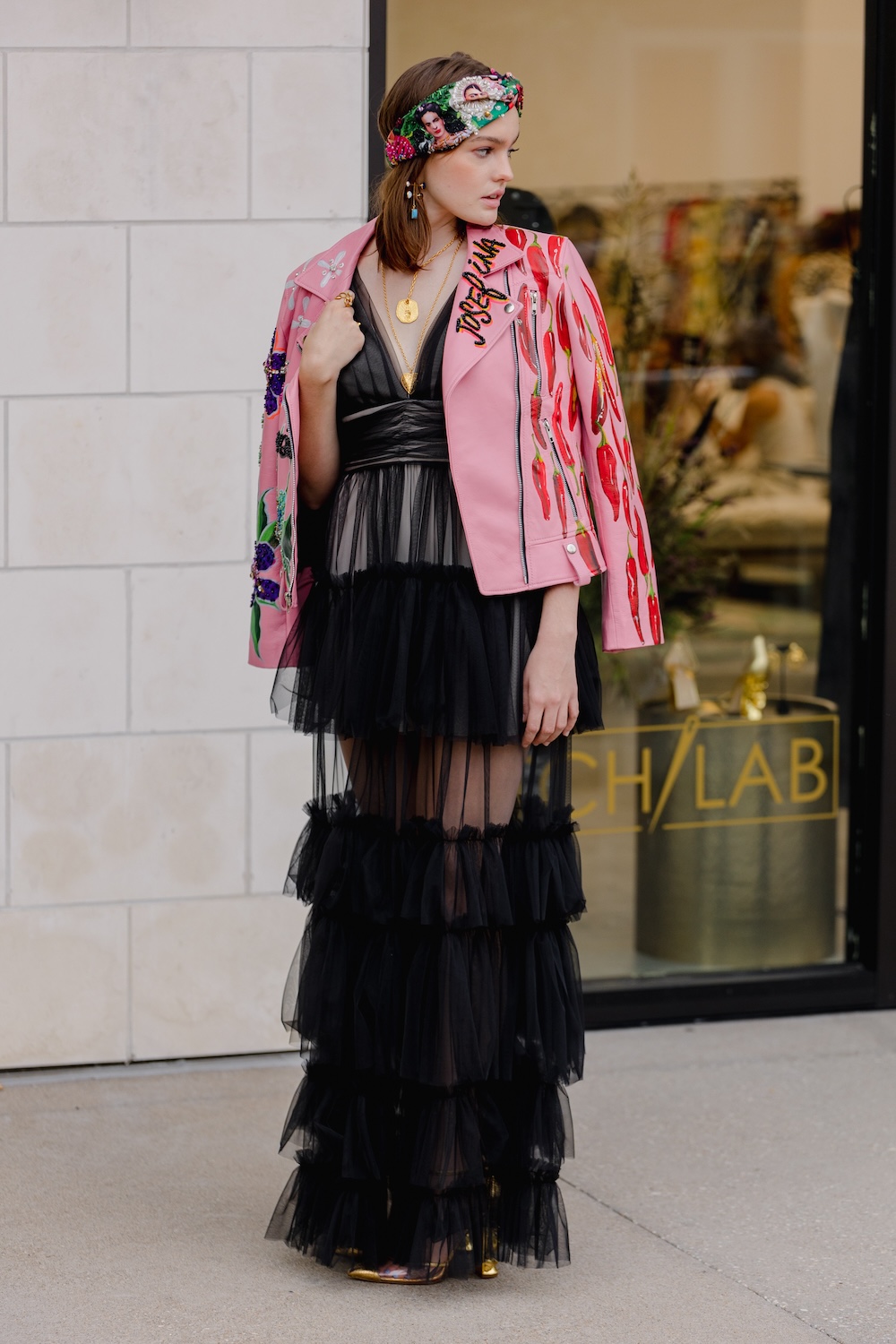 Mujer posa con un vestido negro con transparencias frente al pop-up de Stitch Lab.