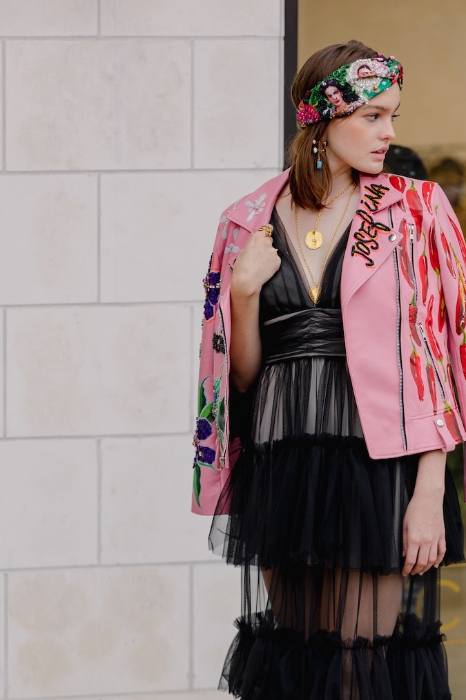 Mujer posa con un vestido negro con transparencias frente al pop-up de Stitch Lab.