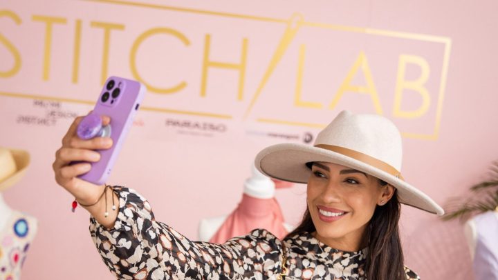 Mujer se toma una selfie frente al cartel de Stitch Lab.