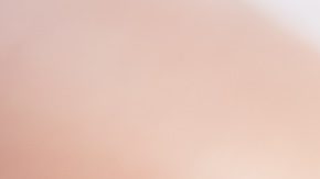 Primer plano de una manicura en color beige y morado con pedrería en algunas uñas.