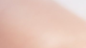 Primer plano de una manicura en color beige y morado con pedrería en algunas uñas.