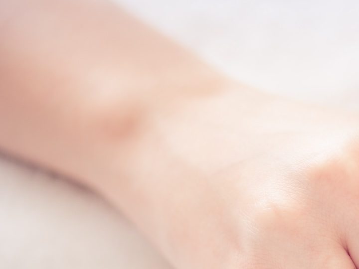 Primer plano de una manicura en color beige y morado con pedrería en algunas uñas.