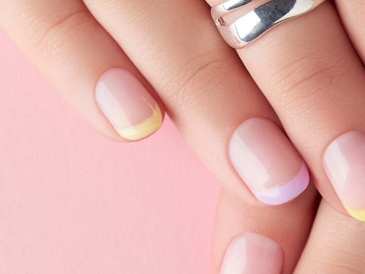 Manos de mujer con manicure francés en colors pastel.