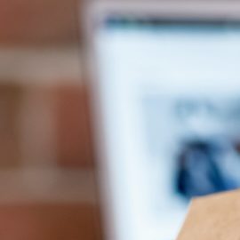 Smartphone con logo de Amazon en pantalla, carrito de compras y laptop por su Big Spring Sale 2024.