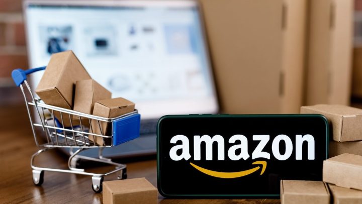 Smartphone con logo de Amazon en pantalla, carrito de compras y laptop por su Big Spring Sale 2024.
