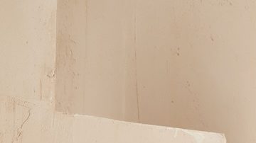 Mujer castaña posa frente a las escaleras con un conjunto primaveral de dos piezas en color camel.