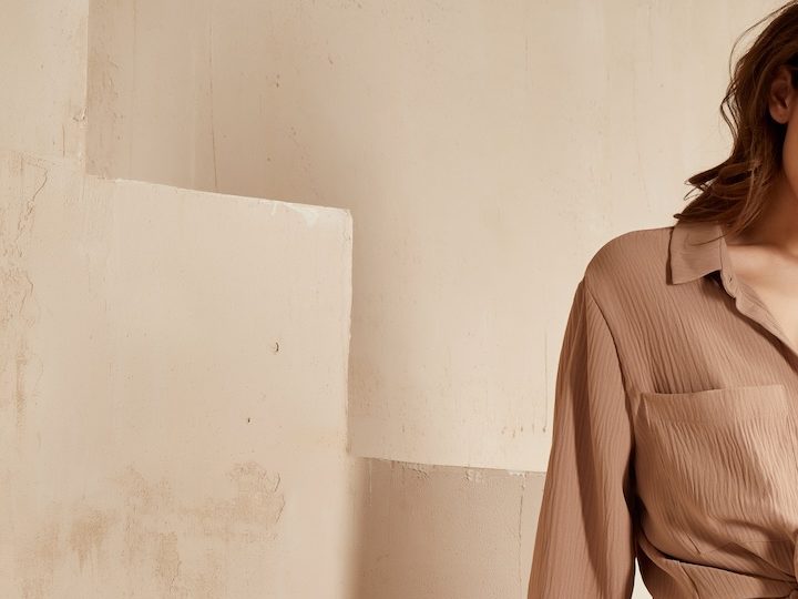 Mujer castaña posa frente a las escaleras con un conjunto primaveral de dos piezas en color camel.
