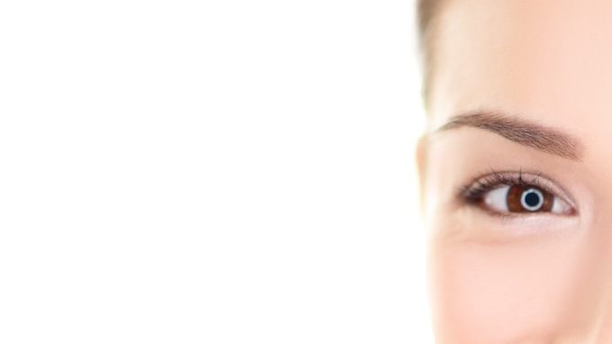 Mujer se aplica bálsamo labial con color mientras sonríe.