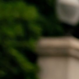 Una chica con blusa naranja posando cerca de escaleras iluminadas por el sol.