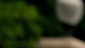 Una chica con blusa naranja posando cerca de escaleras iluminadas por el sol.