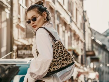 Mujer posa en la calle usando una bolsa en el hombro con estampado de leopardo.