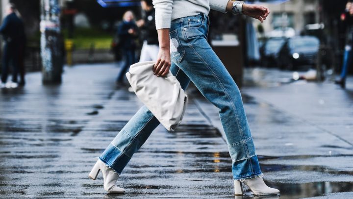Mujer camina por la calle usando jeans bootcut y botines durante Paris Fashion Week en 2019.