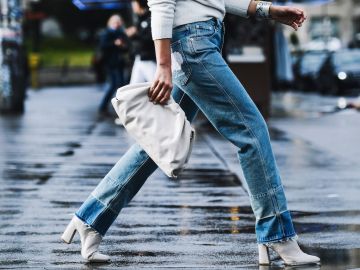 Mujer camina por la calle usando jeans bootcut y botines durante Paris Fashion Week en 2019.