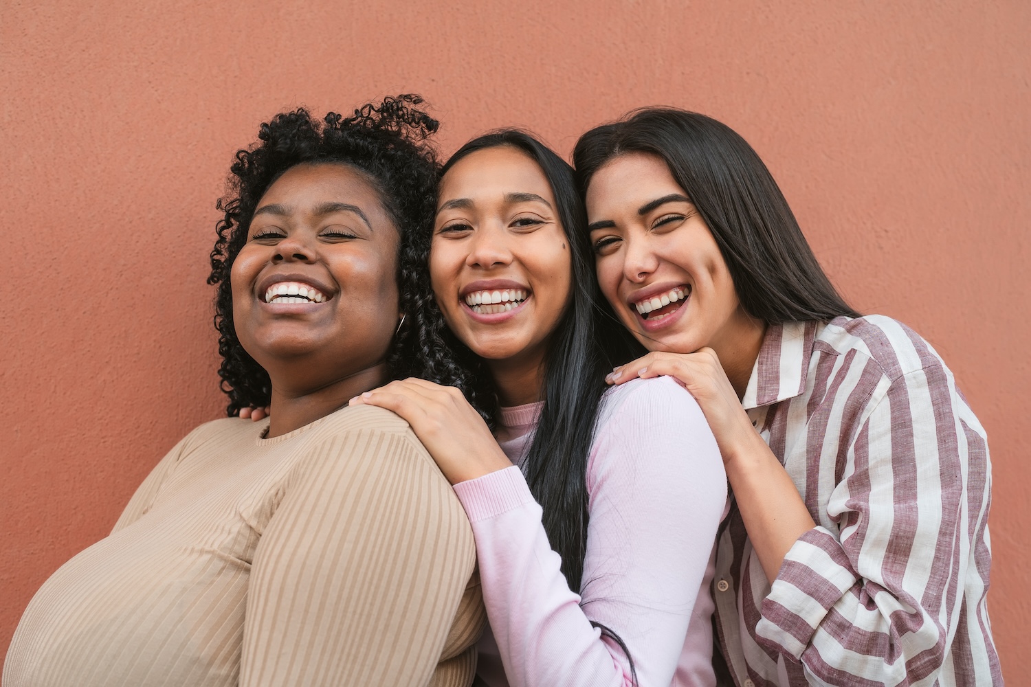 Felices amigas multirraciales divirtiéndose sonriendo juntas frente a la cámara.