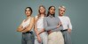 Diversas mujeres con mucha confianza mirando la cámara mientras están de pie contra un fondo de estudio